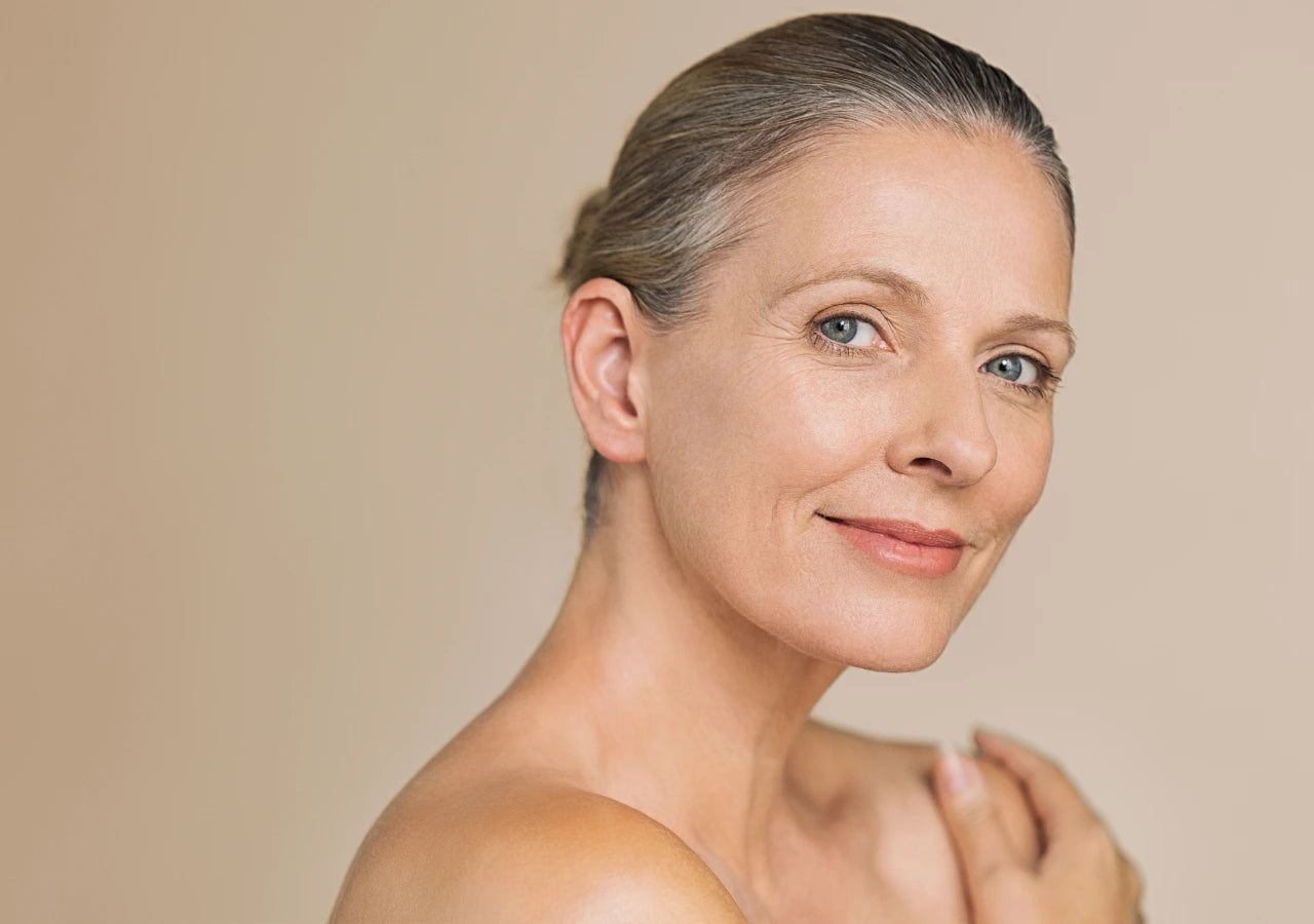 Anti-aging skincare products for a mature skin woman smiling.