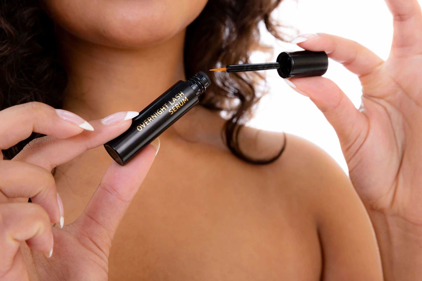 Woman holding AnteAGE Overnight Lash Serum, designed to promote lash growth and strengthen lashes with peptides, growth factors, and botanical extracts.