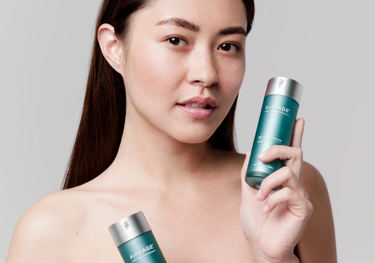 Woman holding up the AnteAGE System, featuring Serum and Accelerator, showcasing an effective anti-aging skincare routine for rejuvenated and youthful-looking skin.