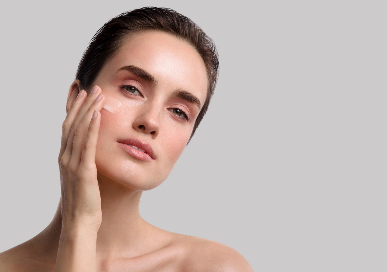 Close-up of a woman applying AnteAGE Serum to her cheek as part of an anti-aging skincare routine to reduce fine lines and wrinkles.