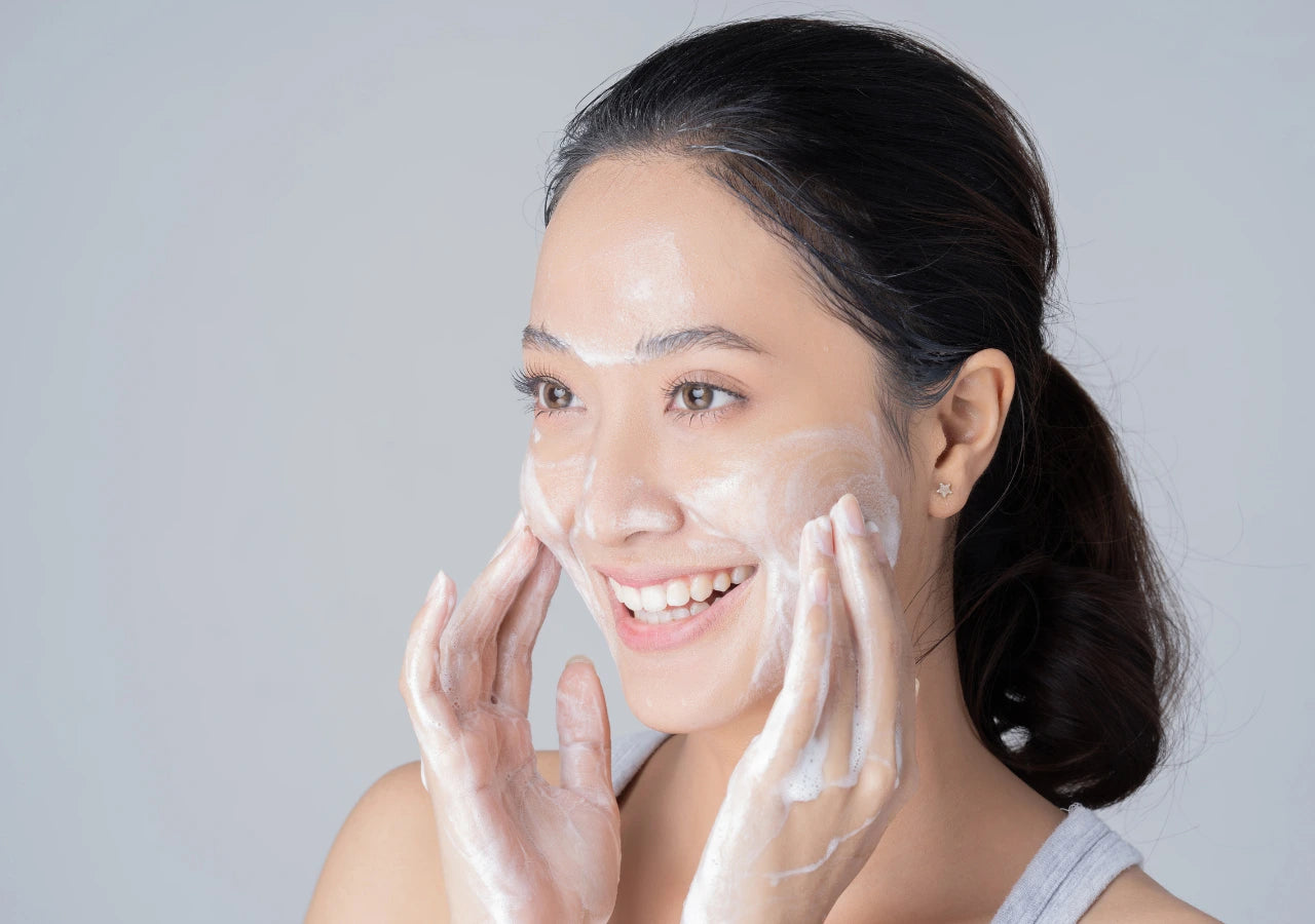 Woman washing her face with a gentle gel foaming wash and smiling.