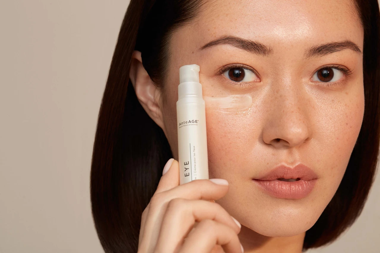 A woman applying AnteAGE eye cream under her eye, showcasing smooth and healthy skin.